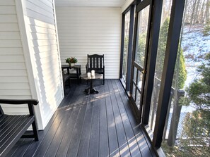 A covered porch with a table and chairs, a bench, and a potted plant.