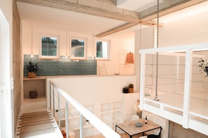 A modern kitchen with a large island, hanging lights, and a view of the outdoors.
