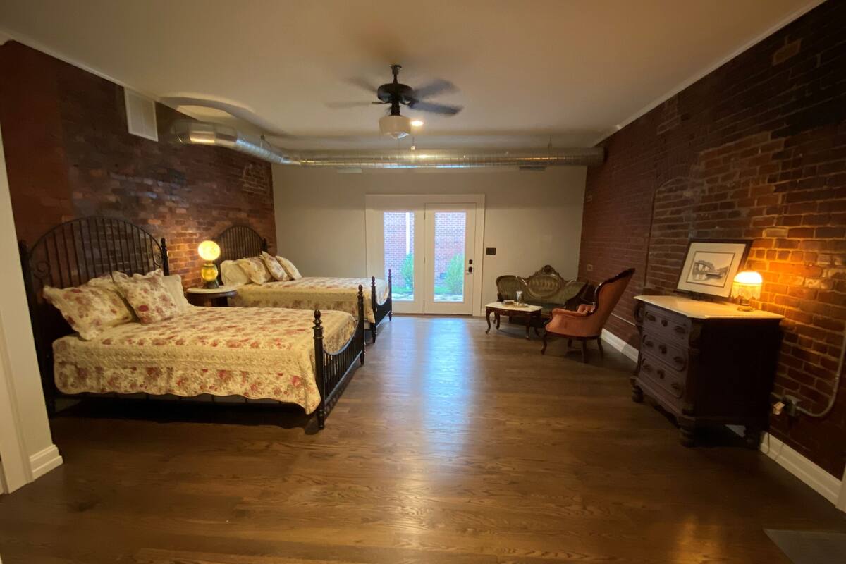 Een slaapkamer met twee bedden, een dressoir, een stoel en een deur naar buiten.