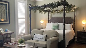 A bedroom with a four-poster bed, a sofa, a coffee table, and a ceiling fan. - Belle Louise Historic Guest House (Paducah)