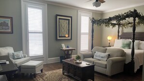 A cozy living room with a four-poster bed, a coffee table, and a fireplace. - Belle Louise Historic Guest House (Paducah)