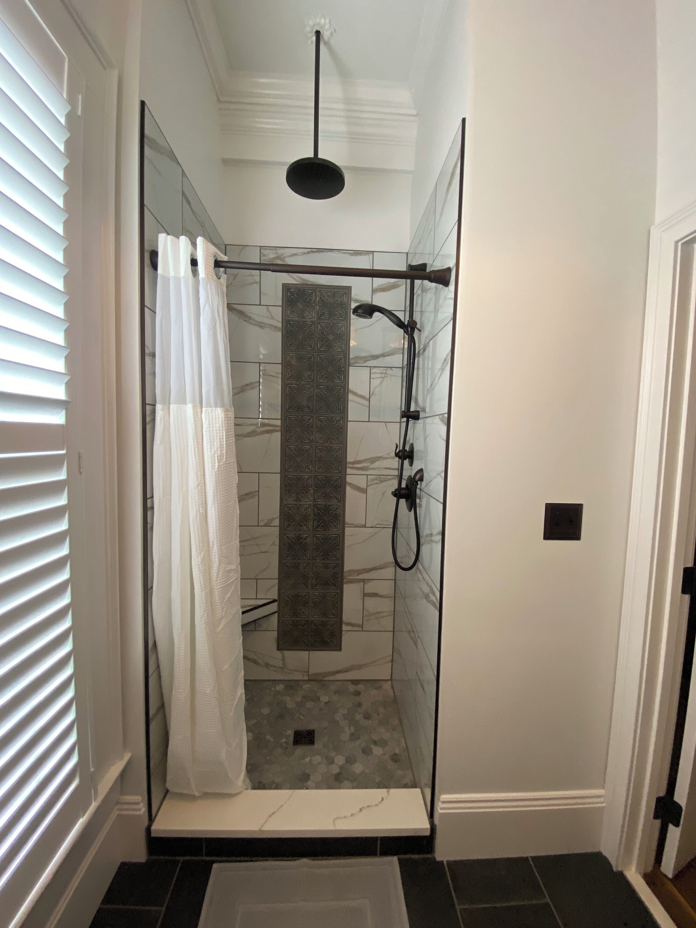 A walk-in shower with a glass door, a showerhead, and a towel rack.