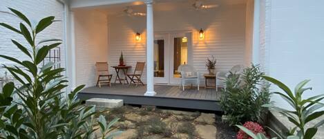 A modern house with a covered porch, stone pathway, and potted plants.
