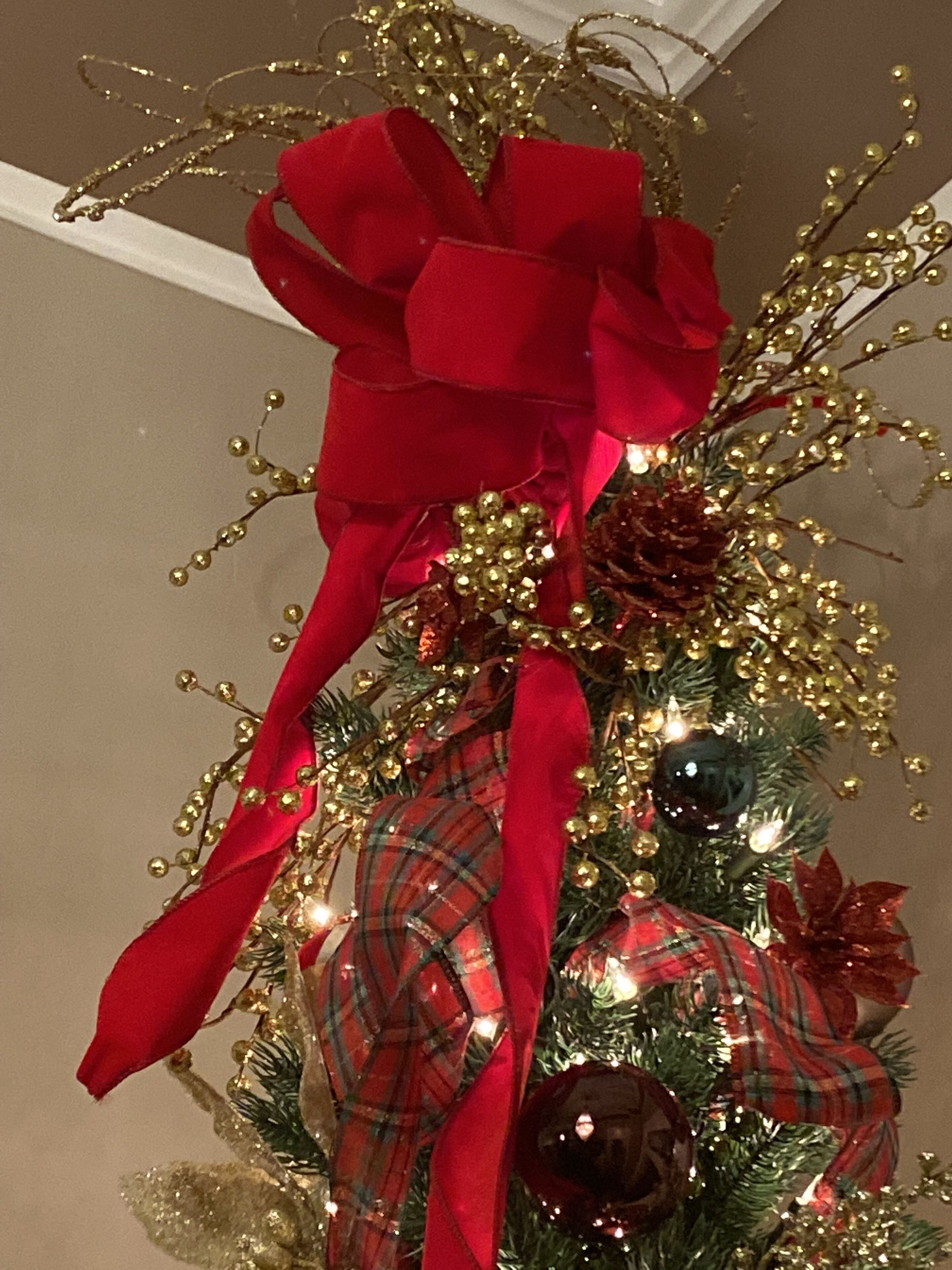 A decorated Christmas tree with a large red bow, golden ornaments, and lights.
