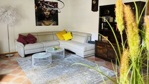 A living room with a sectional sofa, a round coffee table, a floor lamp, a clock, and a bookshelf. - Historic vacation home on the Main, 110 sqm, large terrace, modern and renovated (Mainz-Kostheim)