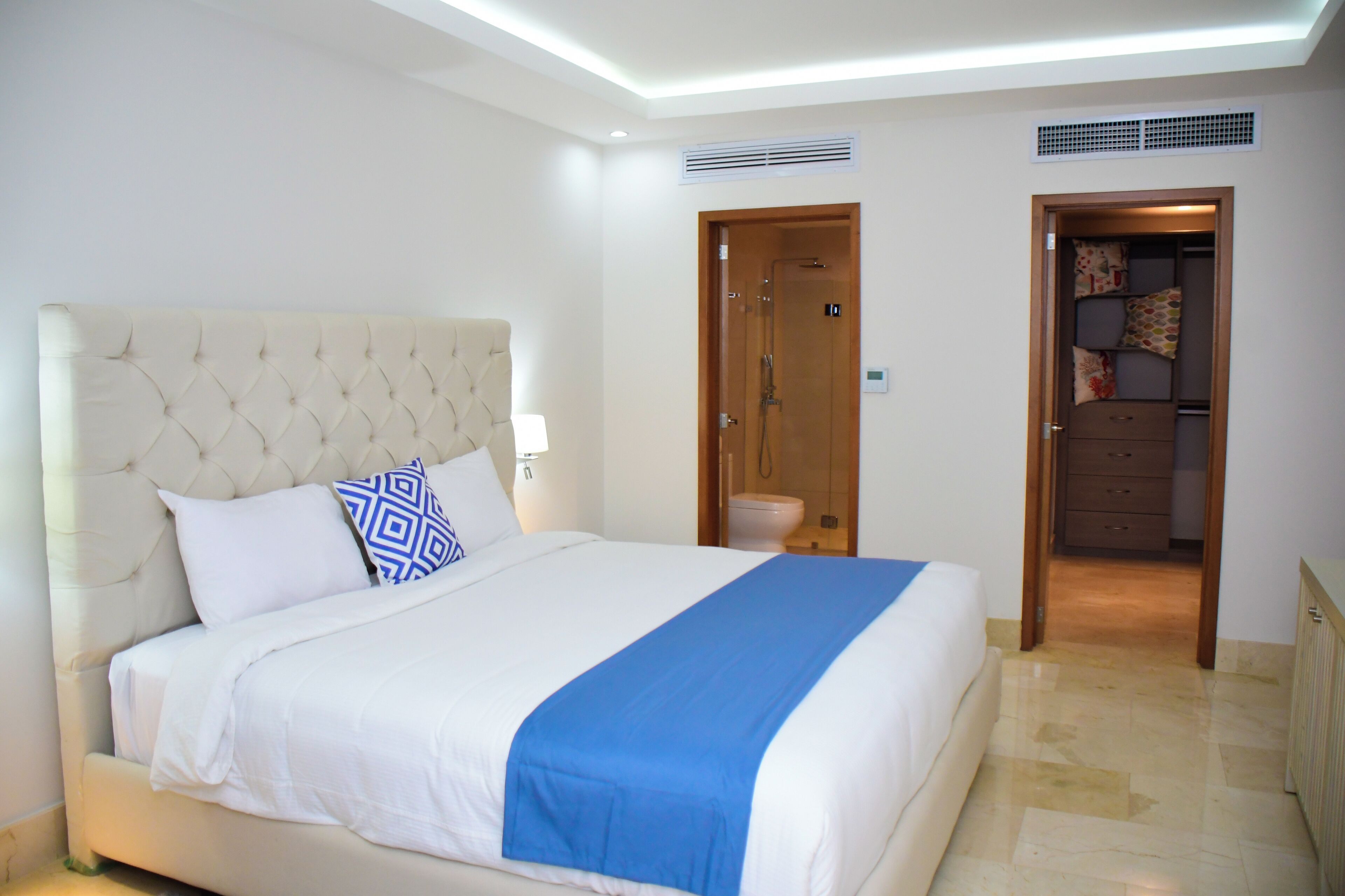 Un dormitorio con una cama grande, una puerta de madera y un baño visible a través de ella.