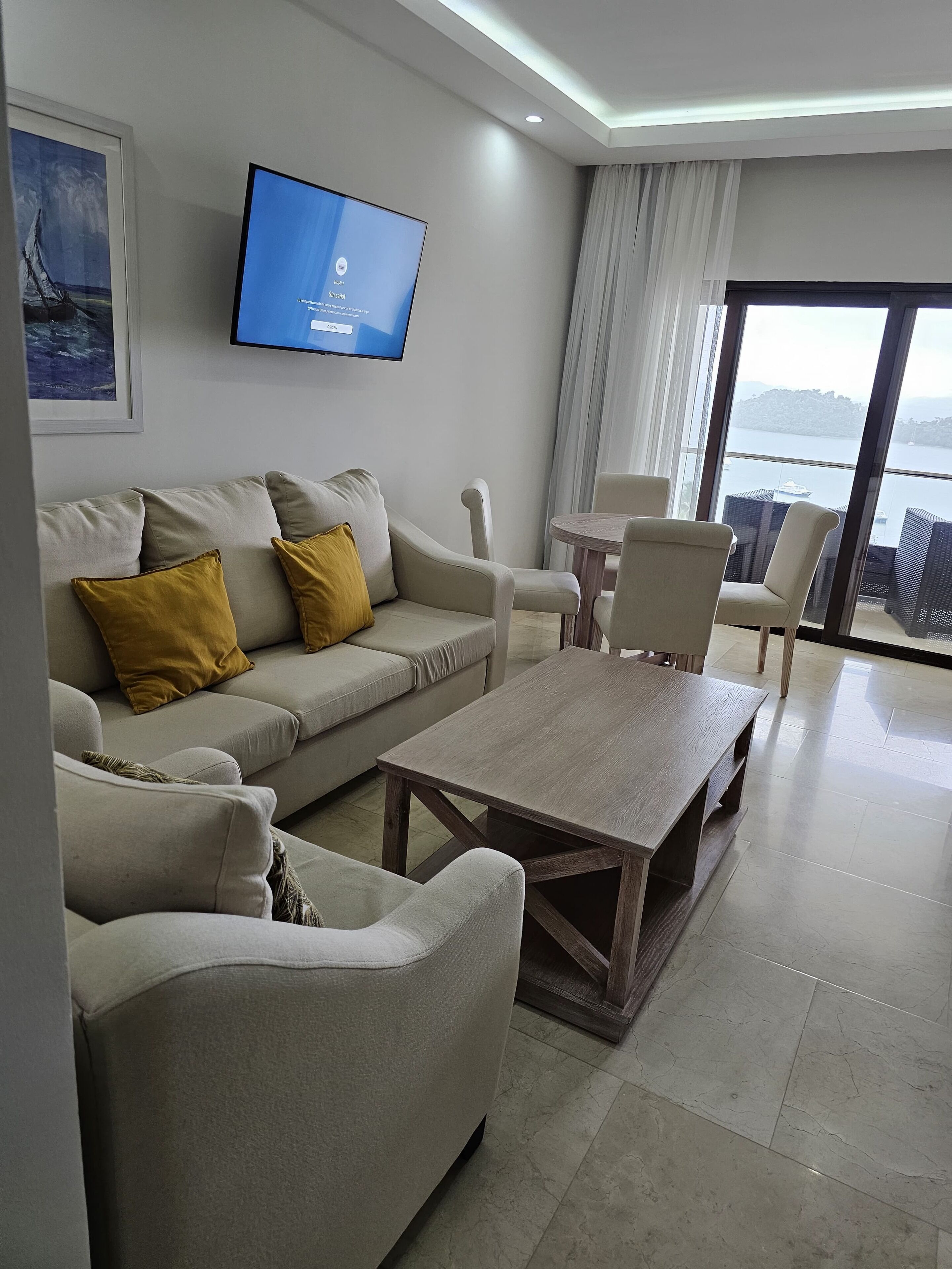 Uma sala de estar moderna com sofá, mesa de centro e TV de tela plana fixada na parede.