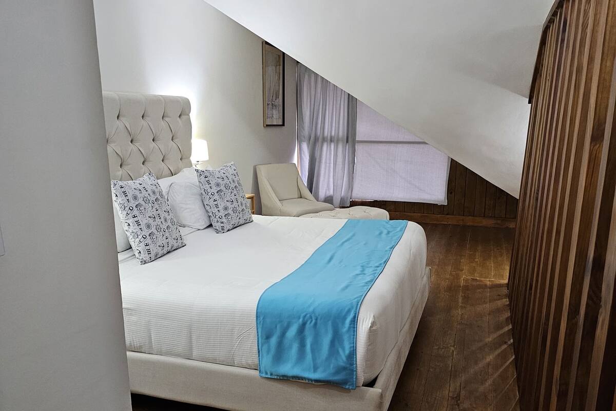 Een slaapkamer met een bed, een stoel en een houten vloer.