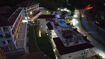 Een meerlaags hotel met een zwembad op het dak en een terras.