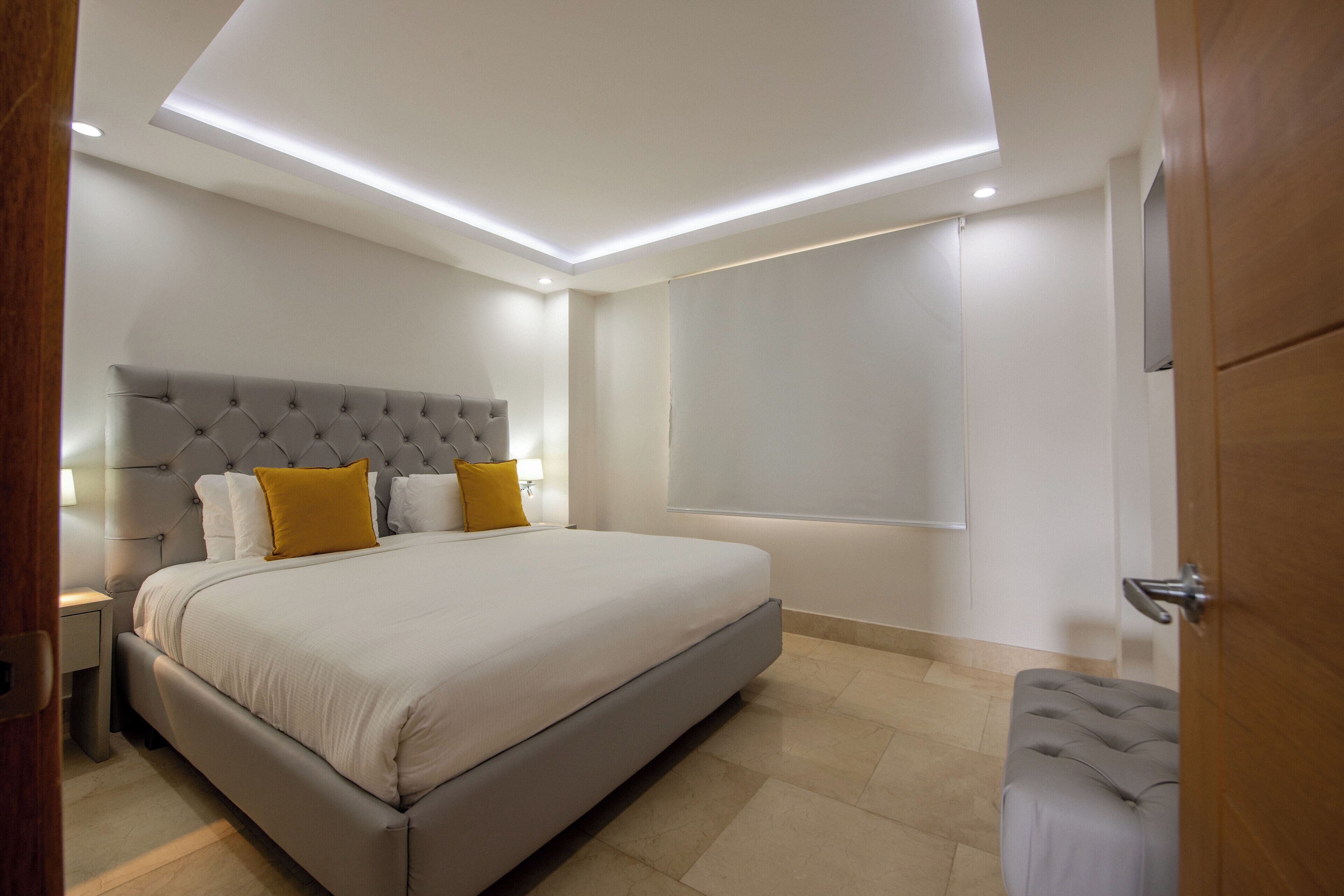 A modern bedroom with a large bed, a tufted headboard, and a bedside table.