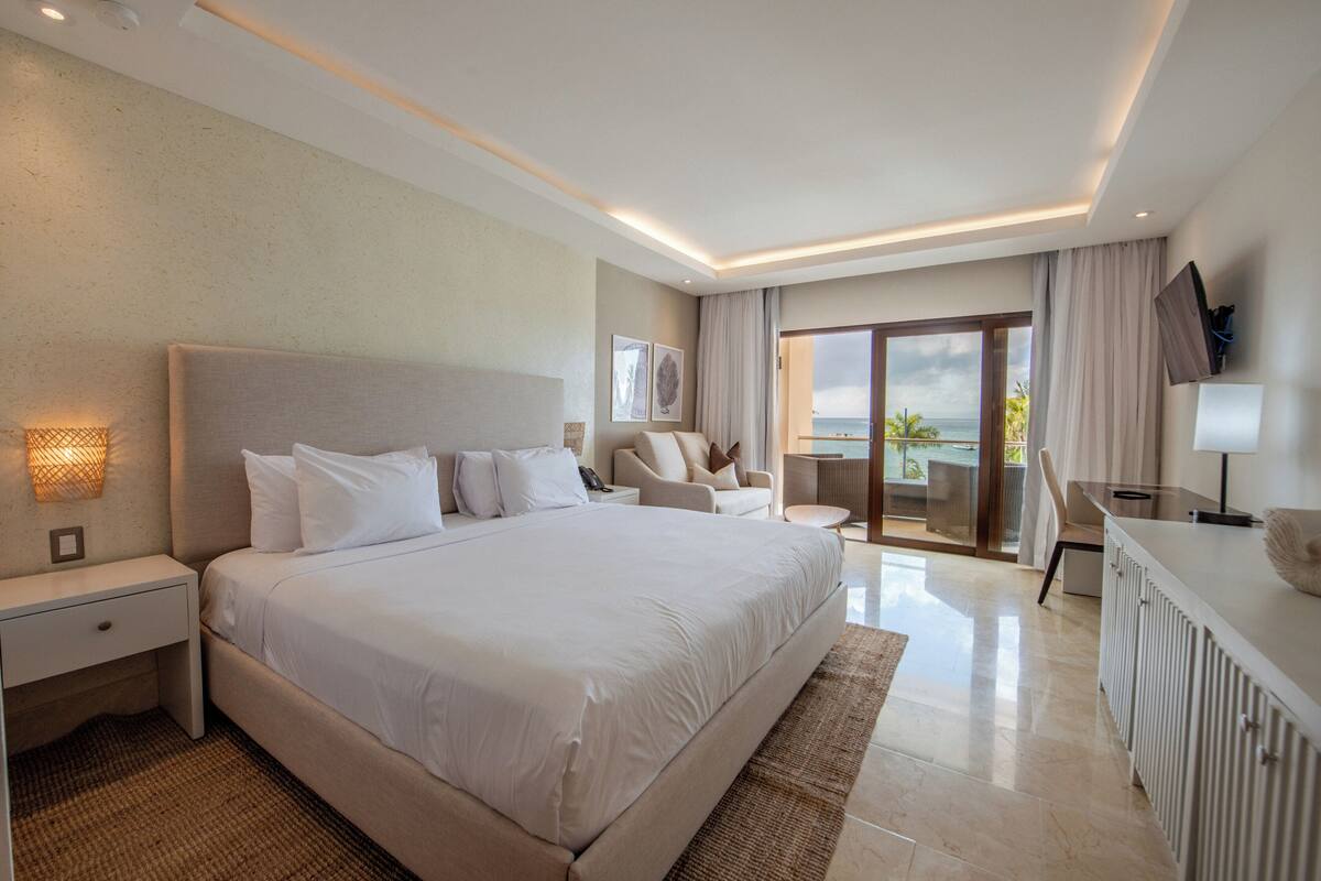 Een moderne hotelkamer met een groot bed, een bureau, een stoel, een televisie en een balkon met uitzicht.