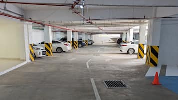 A multi-level parking garage with concrete floors, yellow and black striped barriers, and several parked cars.