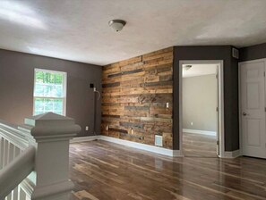 Spacious room with a unique wooden wall feature and a door leading to another room.