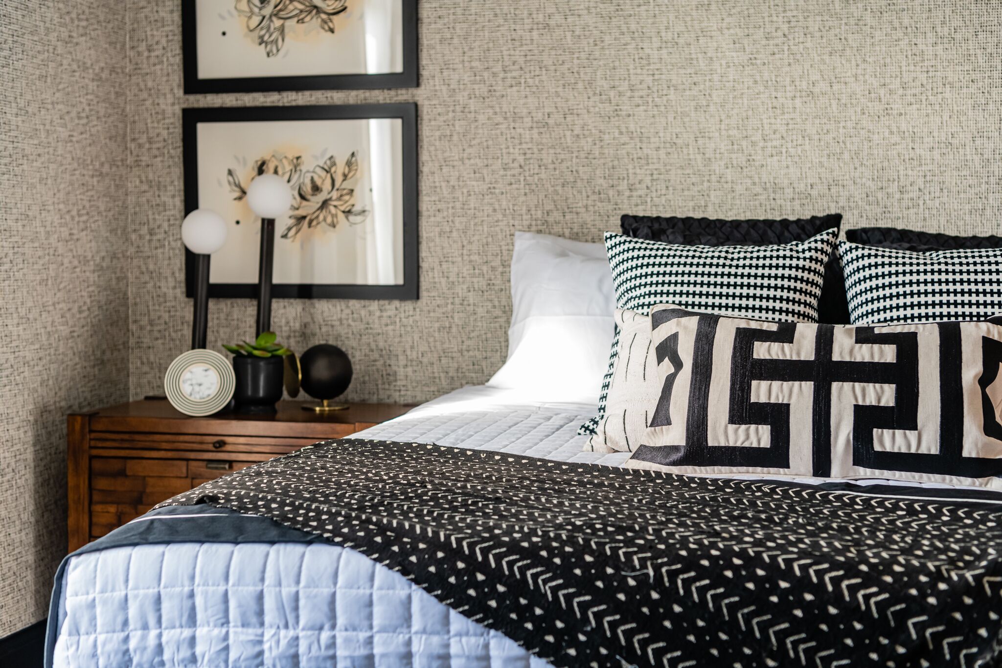 A bedroom with a bed, a nightstand, framed artwork, and a clock.