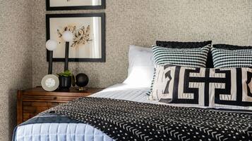 A bedroom with a bed, a nightstand, framed artwork, and a clock.