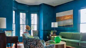 A room with a blue wall, a green sofa, and a patterned armchair. - The Historic Magnolia House (Greensboro)