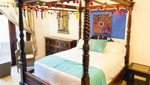 A four-poster bed with a wooden frame and colorful tassels, a small bedside table, and a decorative mirror. - Casa Boho 1 (Sayulita)