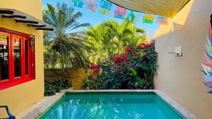 A swimming pool with a tiled deck, surrounded by lush greenery and a colorful mural on the wall. - Casa Boho 1 (Sayulita)