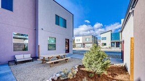 A modern residential area with a patio, a wooden bench, and a small tree.