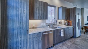 A modern kitchen with dark wood cabinets, stainless steel appliances, and a granite countertop.