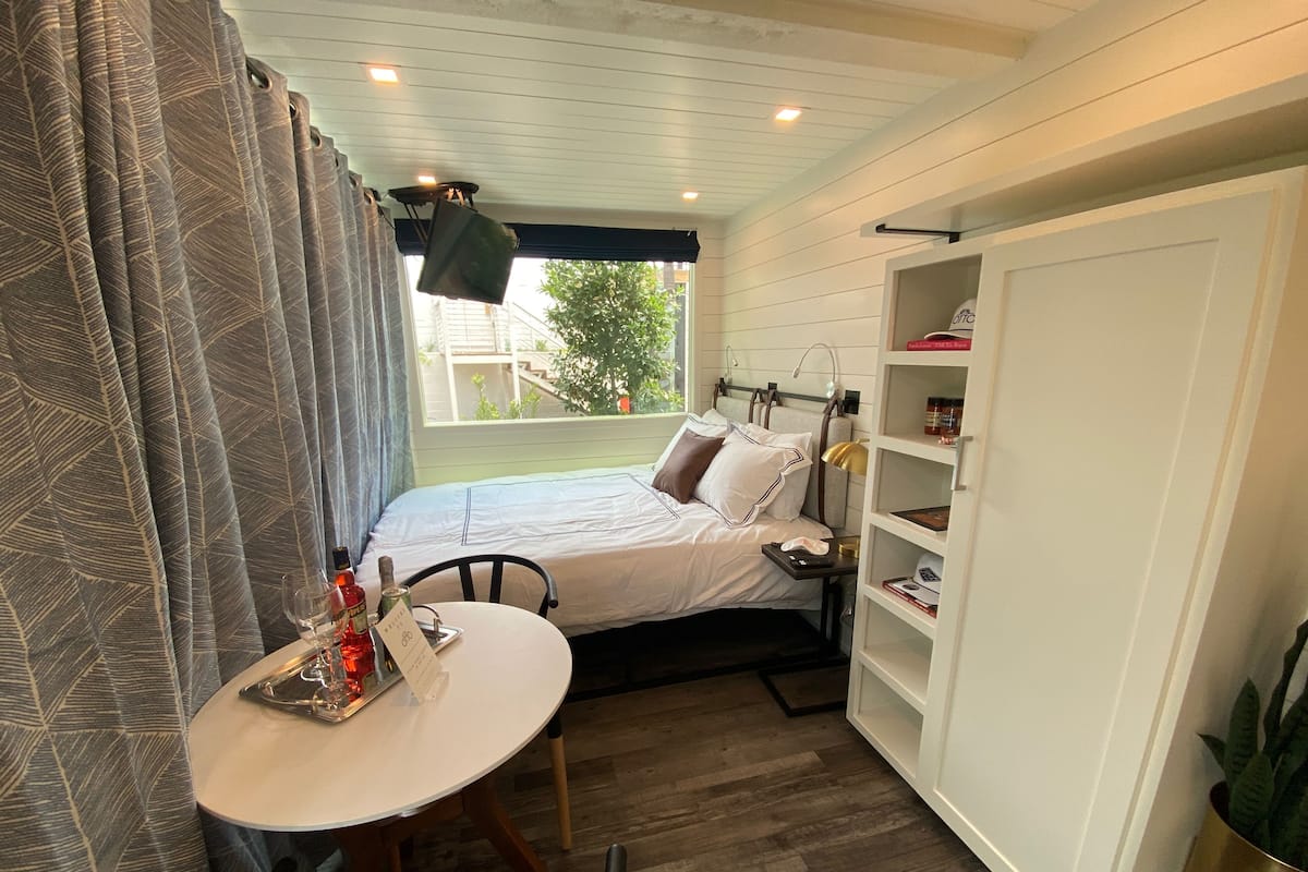 A bedroom with a bed, bedside table, lamp, and a small table with a chair.