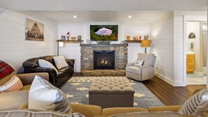 A living room with a fireplace, a sofa, a chair, and a rug. - Gratitude Up North On Round Lake (Hayward)