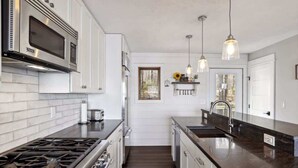 A modern kitchen with white cabinets, stainless steel appliances, and a black countertop. - Gratitude Up North On Round Lake (Hayward)