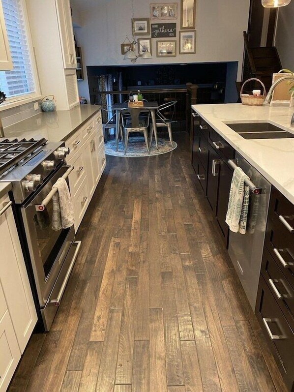Una cocina moderna con suelo de madera, electrodomésticos de acero inoxidable y una zona de comedor con una mesa redonda y sillas.