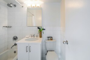 A modern bathroom with a white sink, mirror, and toilet.