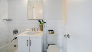 A modern bathroom with a white sink, mirror, and toilet.