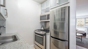A compact kitchen with a stainless steel refrigerator, microwave, stove, and oven.