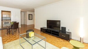 Un soggiorno moderno con una TV a schermo piatto, un tavolino in vetro e un'area pranzo con sedie e tavolo.