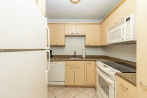 A kitchen with a dishwasher, stove, microwave, and a sink.