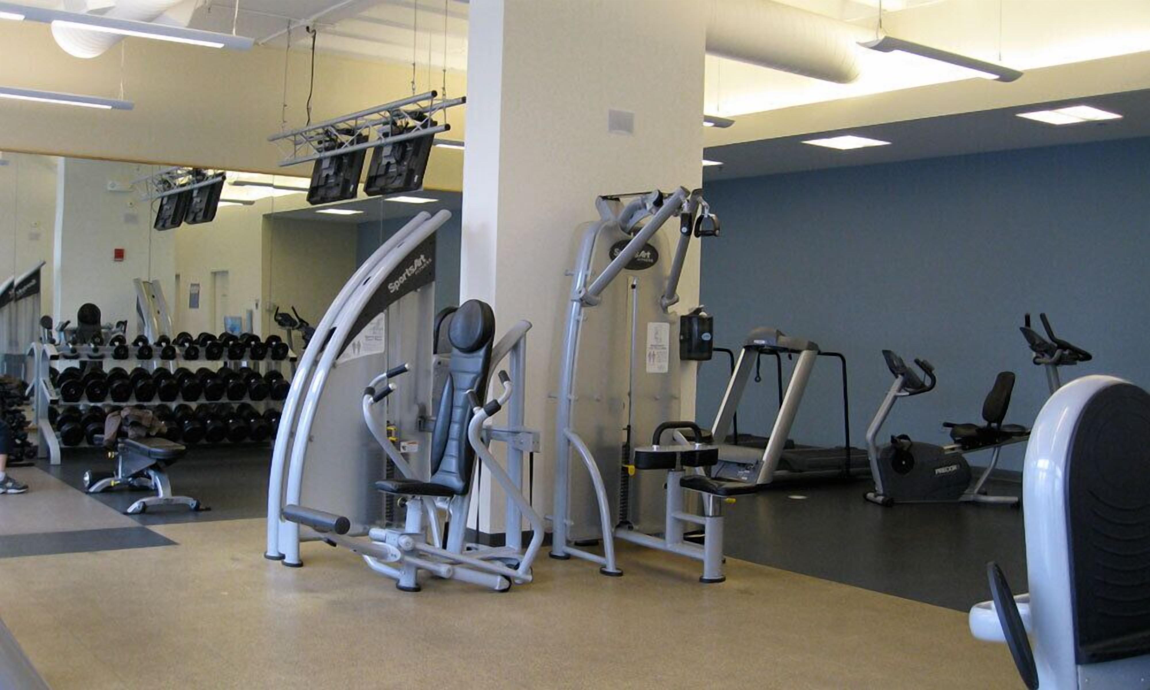 A gym with various exercise equipment, including a treadmill, elliptical, and weight machines.