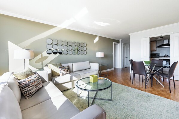 A modern living room with a sofa, coffee table, and dining area with chairs.