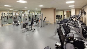 A gym with various exercise machines, mirrors, and a clean, well-lit environment.
