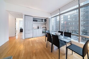 Eine moderne Küche mit weißen Schränken, einer Mikrowelle und einem Essbereich mit einem Glastisch und schwarzen Stühlen.