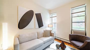 A modern living room with a sofa, armchair, coffee table, and abstract wall art.