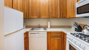 A kitchen with wooden cabinets, a stainless steel sink, a dishwasher, a stove, and a microwave.