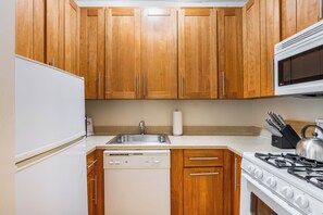 A kitchen with wooden cabinets, a stainless steel sink, a dishwasher, a stove, and a microwave.
