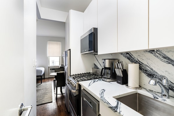 A modern kitchen with a stove, microwave, and sink.