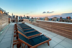 Terraço no topo com várias cadeiras de descanso e vista para o horizonte da cidade.
