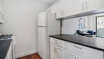A compact kitchen with white cabinets, a black countertop, and a built-in refrigerator.