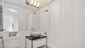 Moderni kylpyhuone, jossa on wc, pesuallas ja kylpyamme.