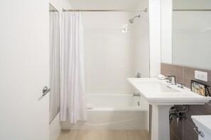 A modern bathroom with a bathtub, a white sink, and a mirror.