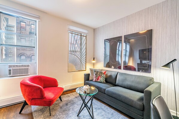 Una sala de estar moderna con una silla roja, un sofá gris y una mesa de centro de vidrio.