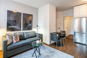 Una sala de estar moderna con un sofá, una mesa de centro de vidrio y un comedor con sillas y una mesa.