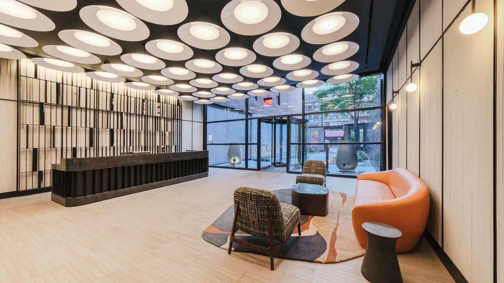 Um lobby moderno com balcão de recepção, área de estar e amplas janelas.