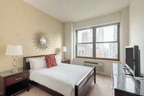 A hotel room with a large bed, two bedside tables with lamps, a TV, and a window with a city view.