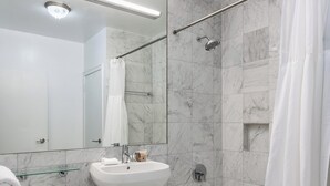 A modern bathroom with a toilet, sink, bathtub, and shower. - Near Central Park | Pet-Friendly & Hardwood Floors (New York)